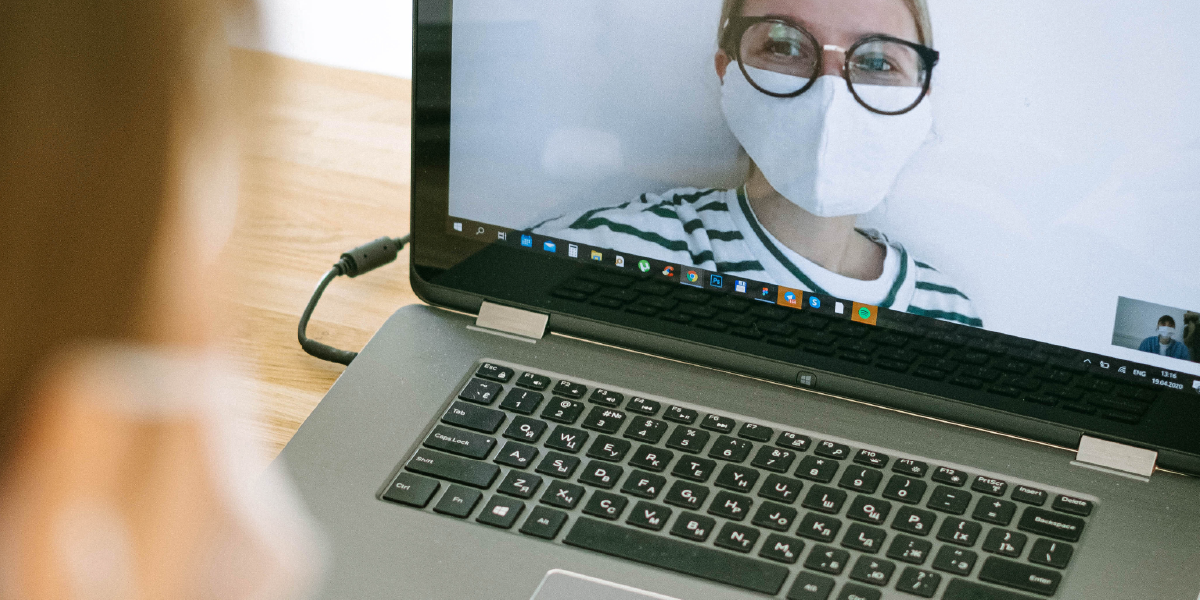 mulher de máscara e óculos na tela do computador
