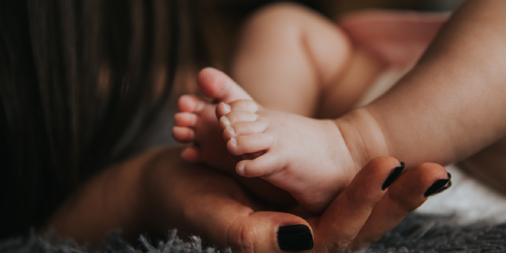 pés de bebê apoiados em mãos de mulher