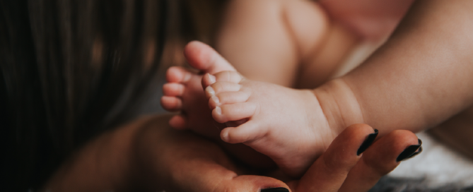 pés de bebê apoiados em mãos de mulher
