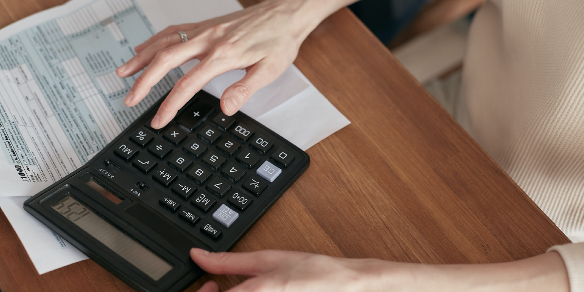 A foto mostra mãos mexendo em uma calculadora