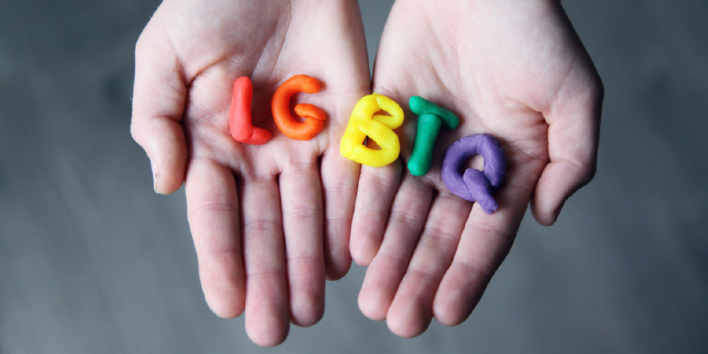 Mãos segurando letras da sigla LGBTQ