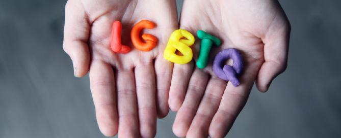 Mãos segurando letras da sigla LGBTQ