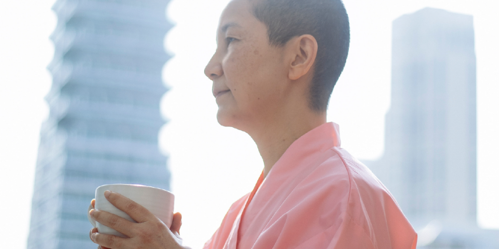 mulher careca asiática segurando xícara de chá