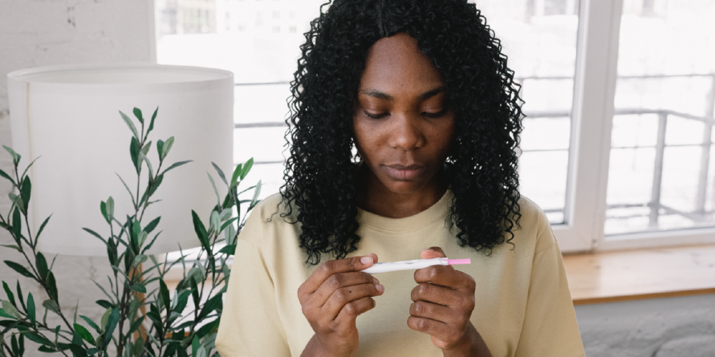 mulher olhando para teste de gravidez