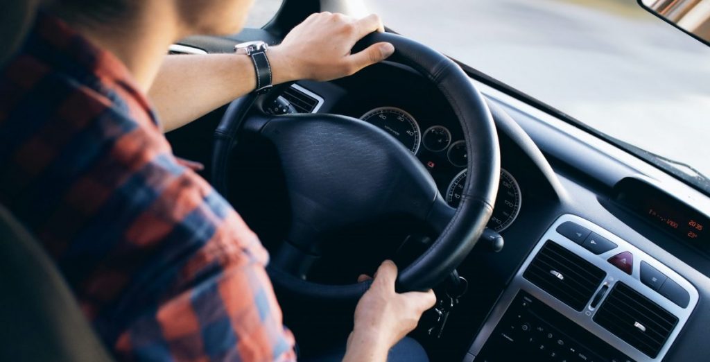 A imagem mostra uma mulher ao volante de um carro, dirigindo.