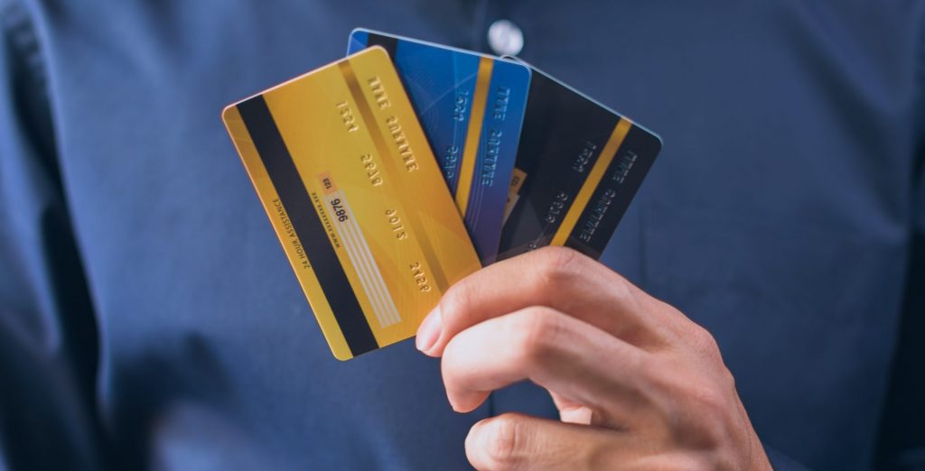 A mão de um homem segurando três cartões de crédito.