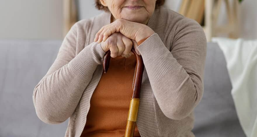 Uma mulher idosa apoiada em sua bengala.