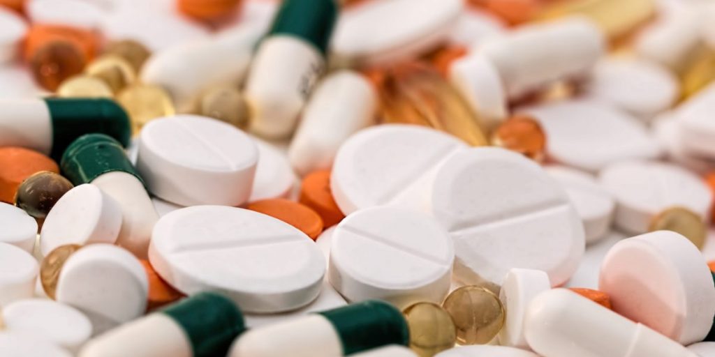 Vários comprimidos de medicamentos de diversas formas e cores.