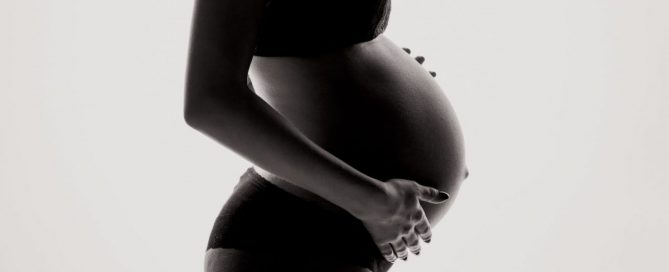 Foto em preto e branco da barriga de uma mulher grávida.