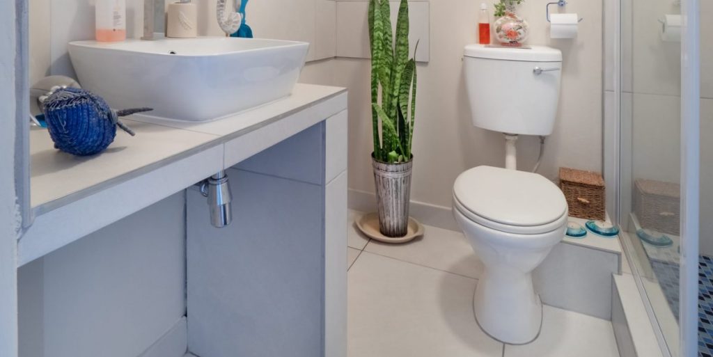 Imagem de um banheiro com uma pia, um balcão e um vaso sanitário.