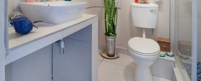 Imagem de um banheiro com uma pia, um balcão e um vaso sanitário.